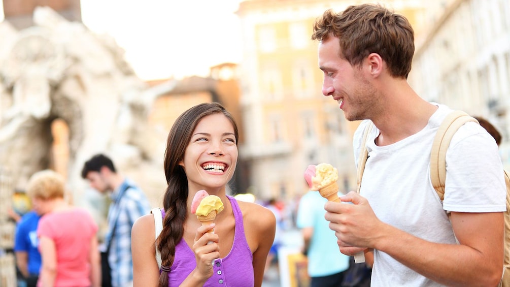 Happy couple enjoying delicious gelato on a hot, sunny day in Rome.