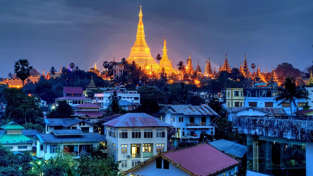 Shwedagon Pagoda shining brightly at night on a hill over the city of Yangon