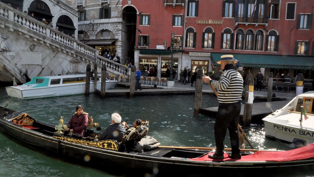 People on gondola ride going under a bridge in Venice Italy 