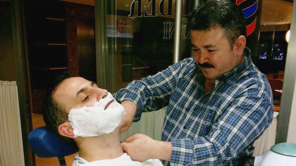 Barber giving a guest a traditional Turkish shave in Istanbul 