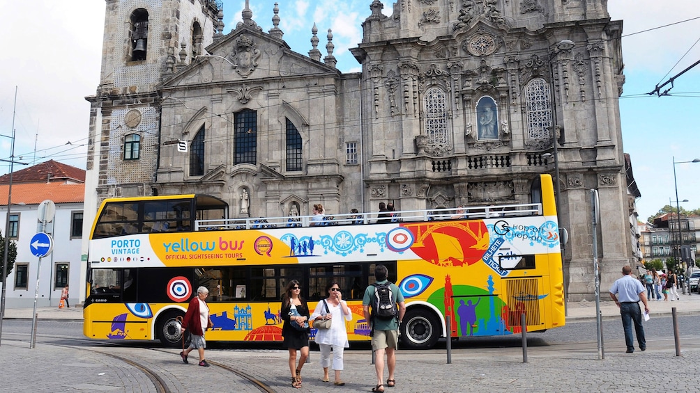 Hop-Of Hop-Off bus parked by a gothic cathedral in Porto