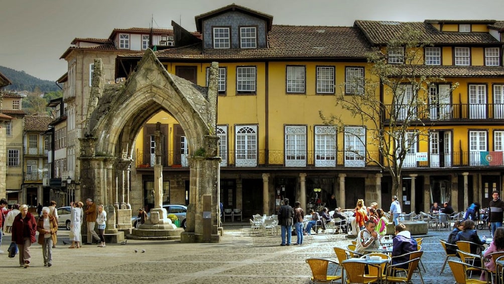 Yellow building and stone archway in Oliveira Plaza in Guimaraes