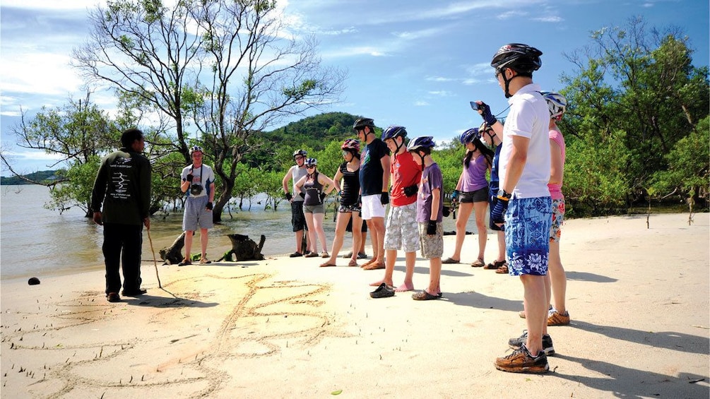Group of people listening to their guide on a beach in Phuket. 