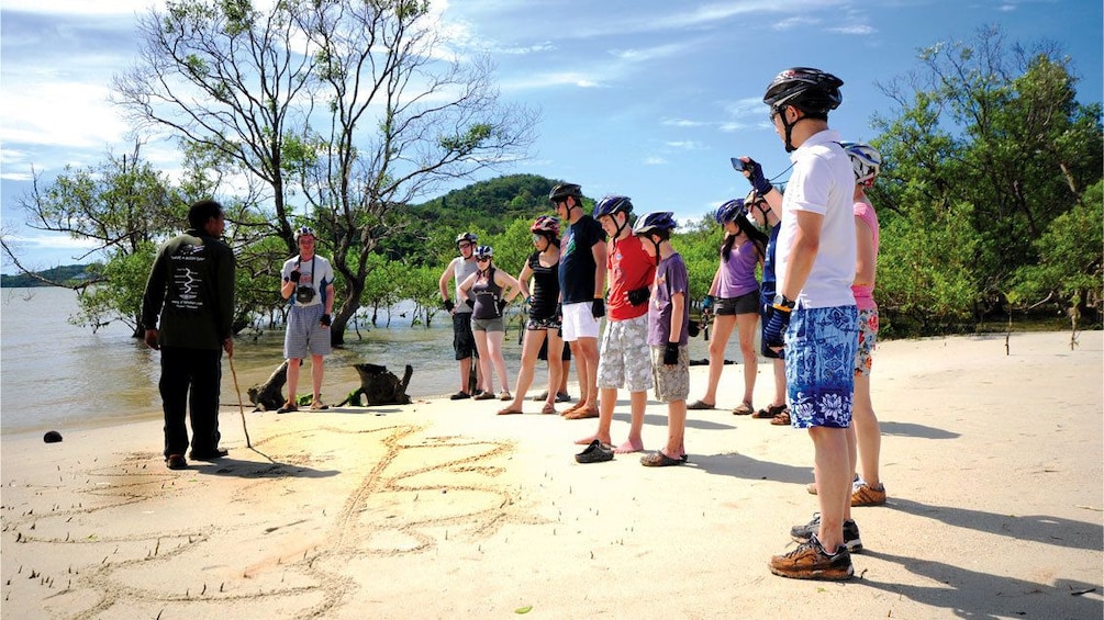 Group of people listening to their guide on a beach in Phuket.