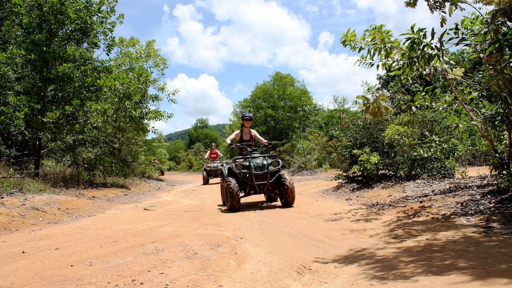 ATV riders going through a dirt path in Phuket.