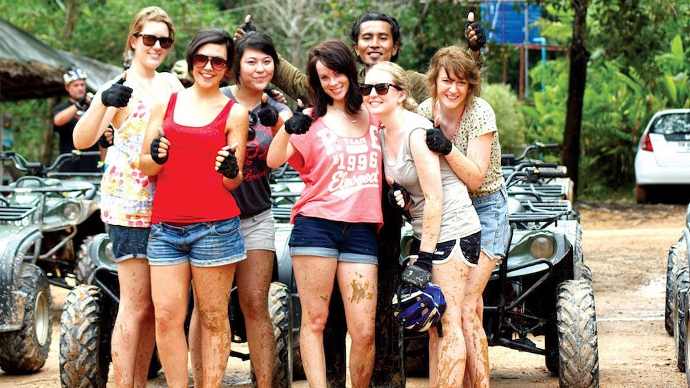 Tour group smiling infront of their ATVs.