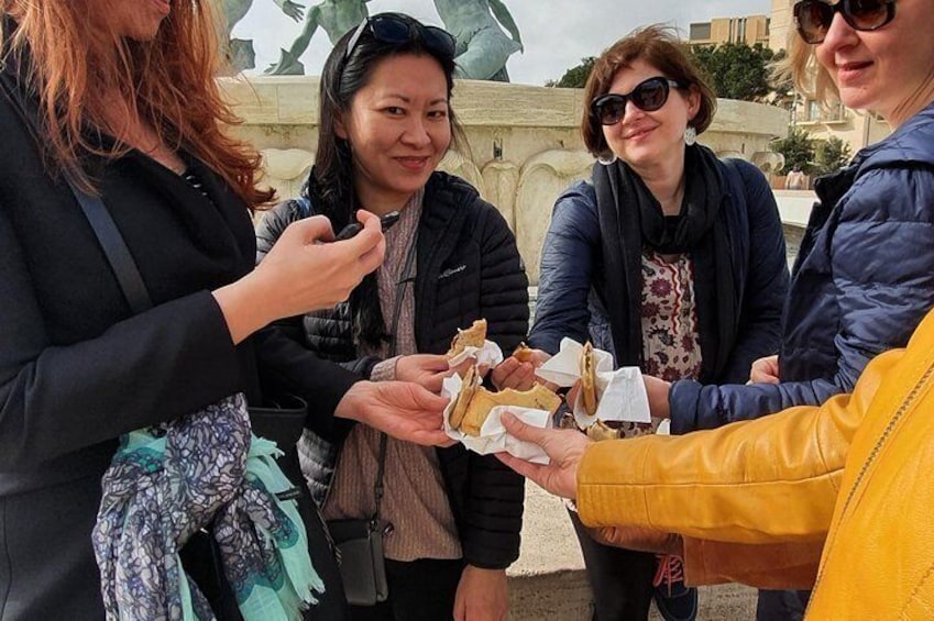 Eating Imqaret at the Triton Fountain.