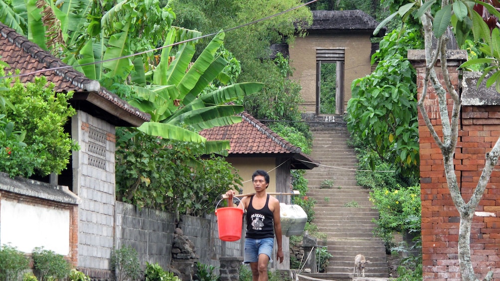A man walking past traditional buildings in Bali