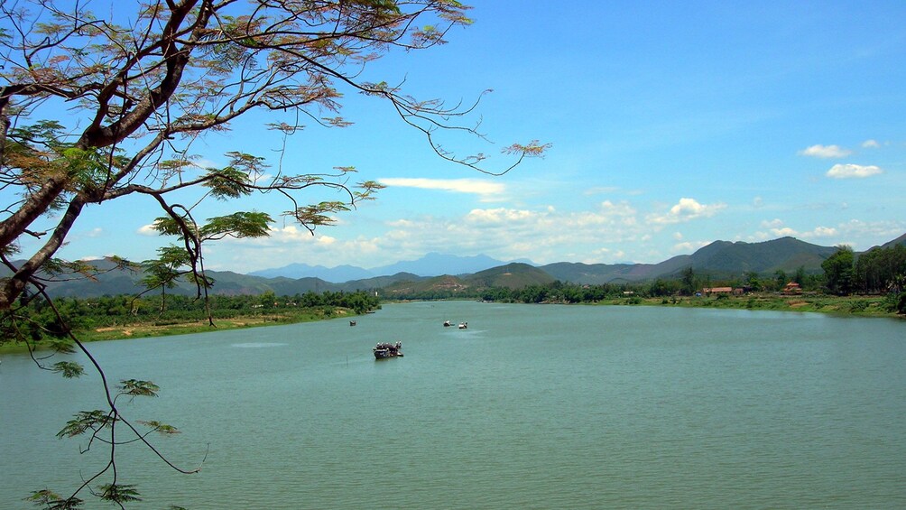 A scenic view of boats sailing down a river and mountains in Hue