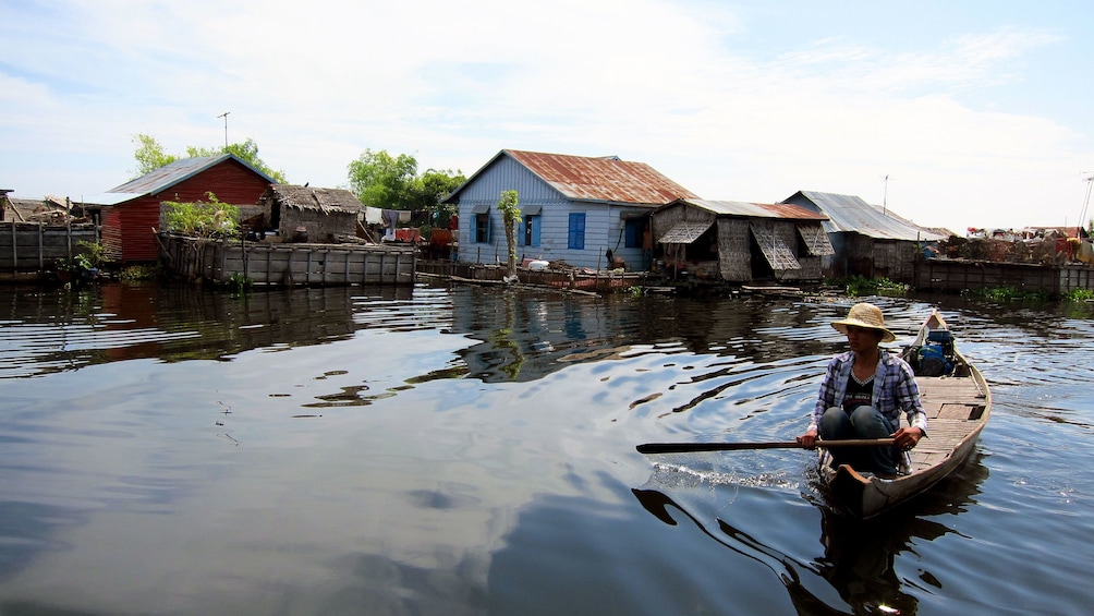 man paddling small boat in village in Siem Reap
