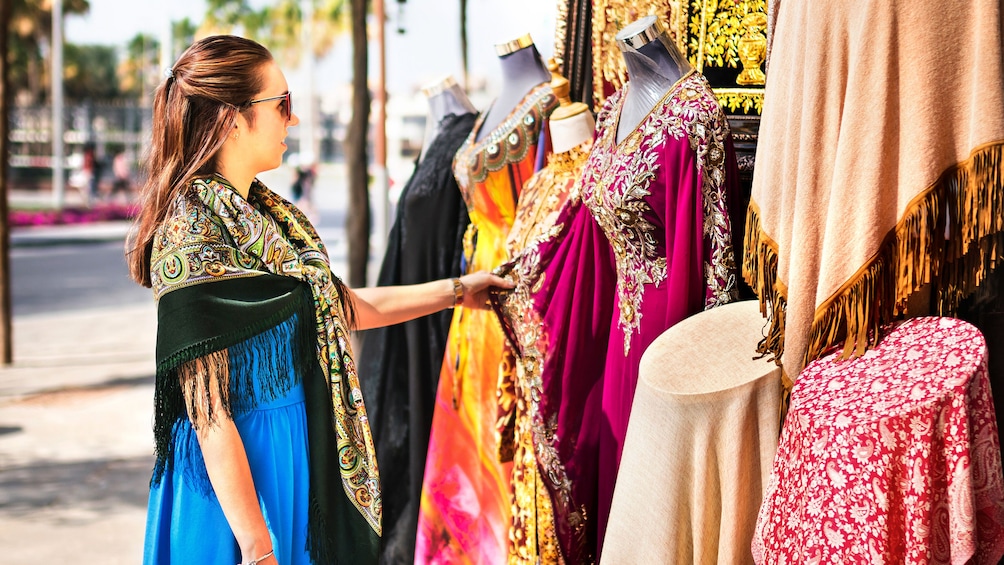 Woman looks at dresses on street in Dubai
