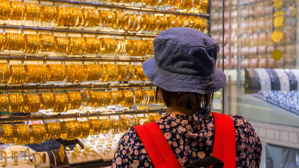 Tourist looks at gold bracelets in Dubai shop