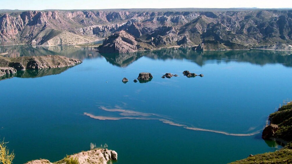 the placid surface of a bright blue body of water in Atuel Canyon