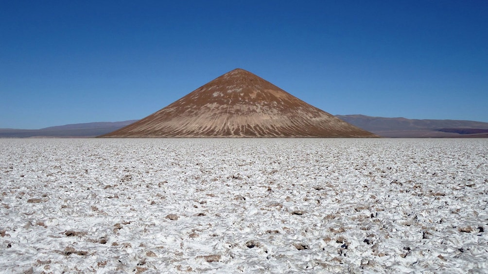 Conical hill rising above the Salinas Grandes salt fields in Argentina
