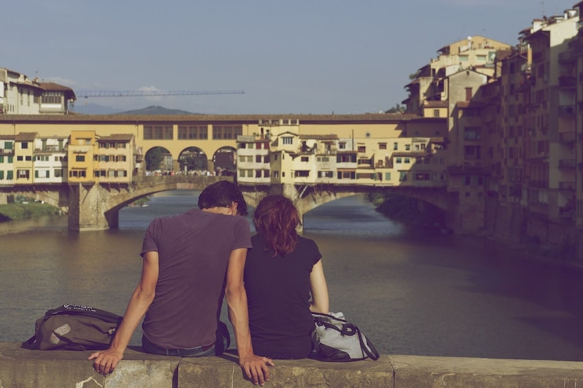 Couple sit over the River Arno in Florence