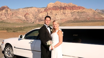 Show item 1 of 5. Happy bride and groom pose for a quick photo next to their limousine with the Red Rock