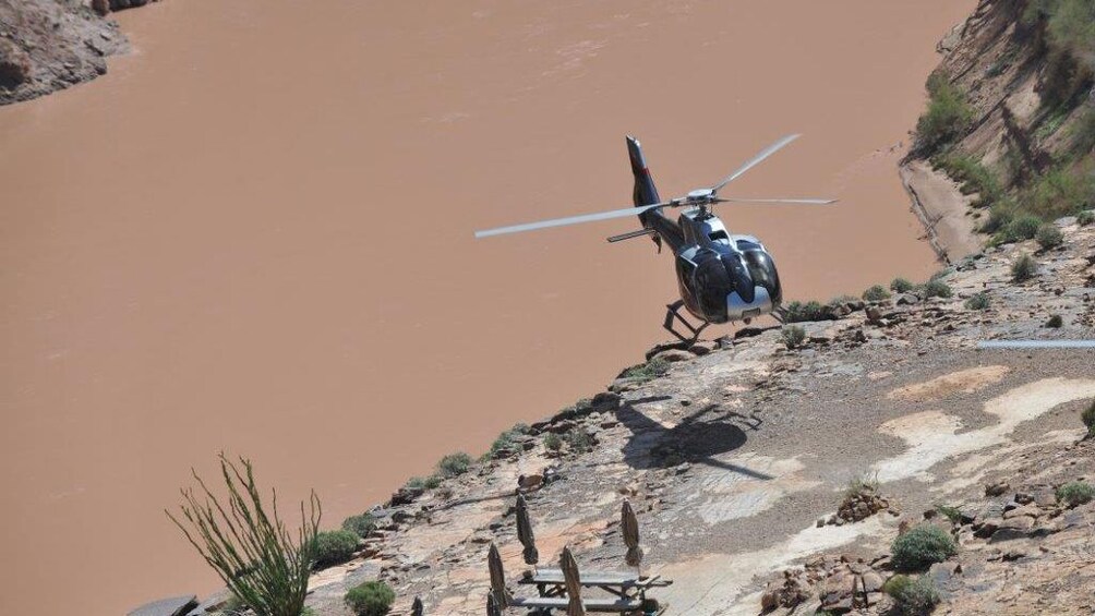 A helicopter takes off on the banks of the Colorado river in the Grand Canyon