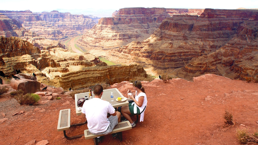 Couple enjoying a delicious meal atop the Grand Canyon with panoramic views