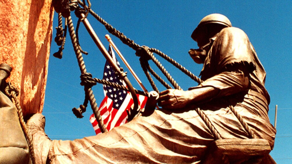 Statue of a construction worker hanging off Hoover Dam with the American flag in hand