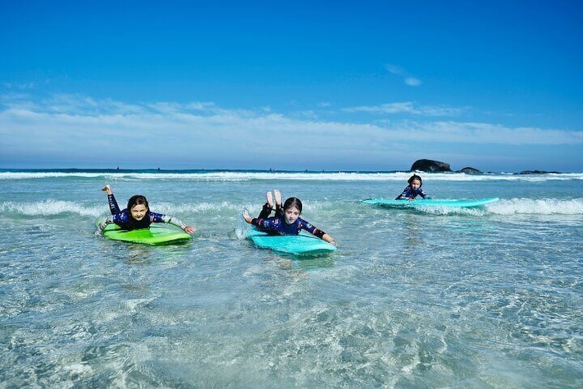 eamwork on the horizon! Three young surfers paddle together, ready to conquer a small wave as a united force.