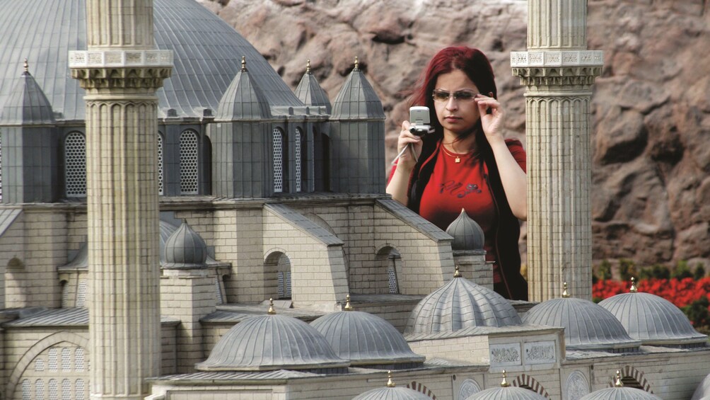 Girl taking a photo of a miniature model building inside Miniatürk in Turkey 