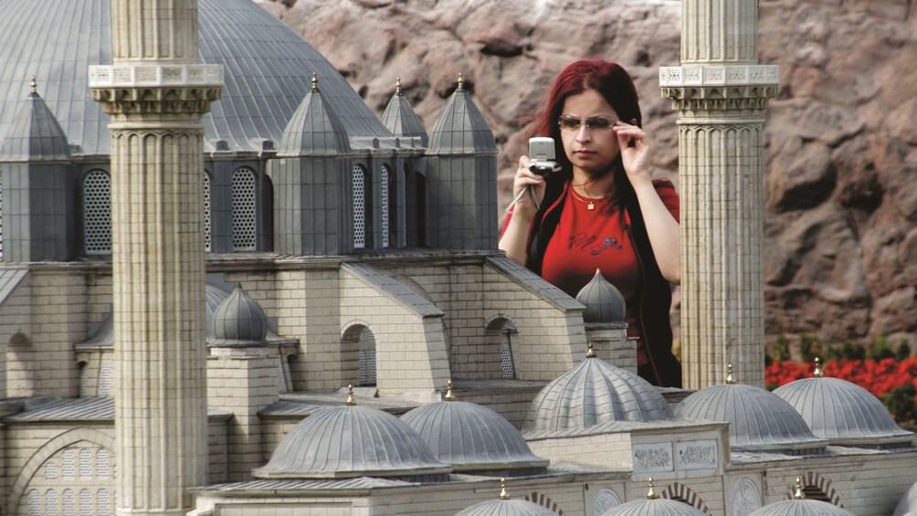 Girl taking a photo of a miniature model building inside Miniatürk in Turkey
