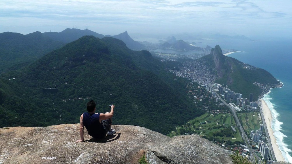 Man enjoying a breathtaking view from the top of Gavea Rock in Rio de Janeiro