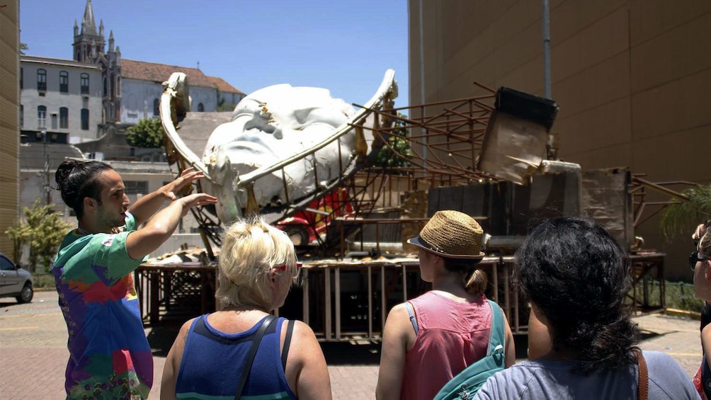 Tour guide with group looking at the skeleton of a Carnival float in Rio de Janeiro