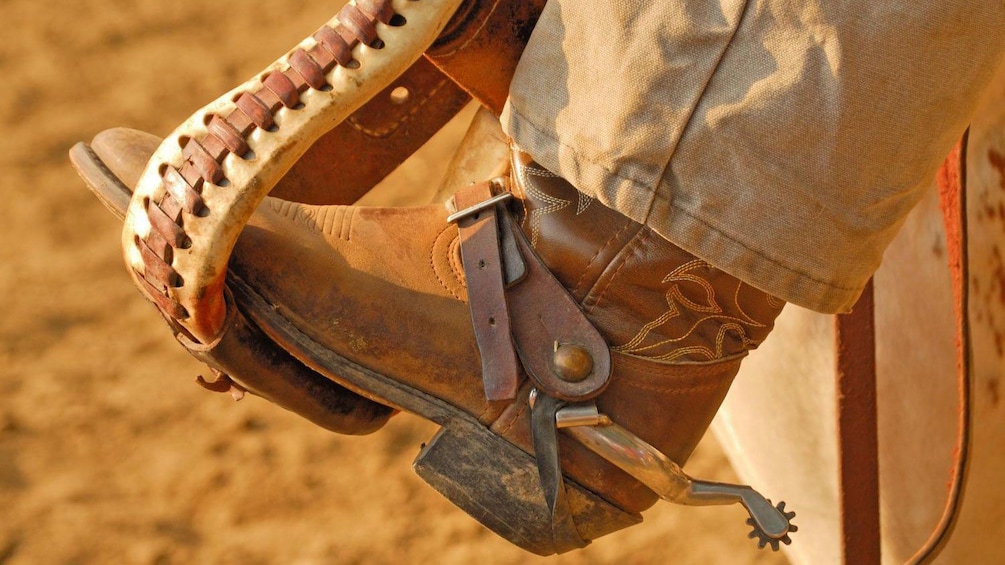 Cargar ítem 3 de 9. Close image of a man stepping into a saddle at the Estancia Santa Susana in Buenos Aires