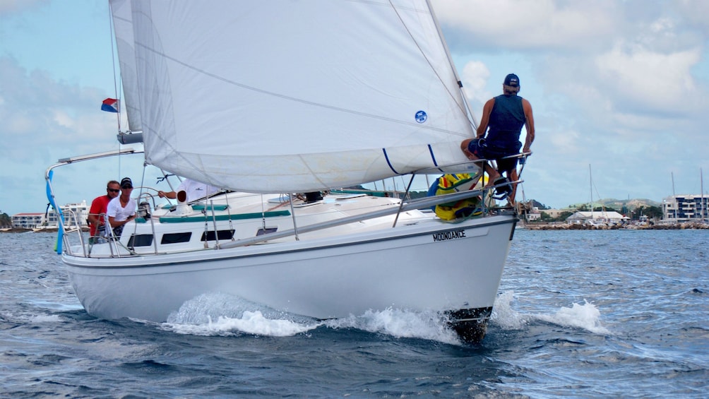 Man standing on the fore of a sailboat cruising off the coast of Saint Martin