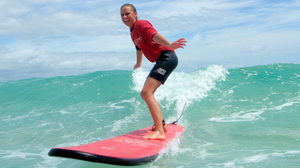 Young lady riding the waves in a group surfing lesson on Byron Bay. 