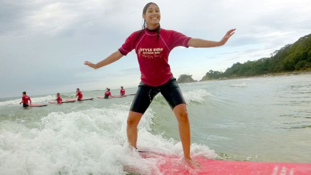 Excited girl surfing in surfing lesson on Byron Bay. 