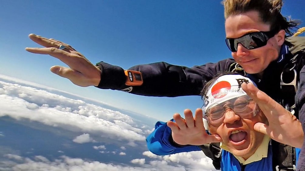 Show item 2 of 4. Two skydivers fastened together falling over Sydney.