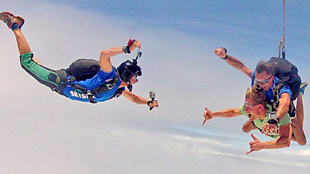 Show item 3 of 4. Falling skydivers getting their picture taken by another skydiver over Sydney.