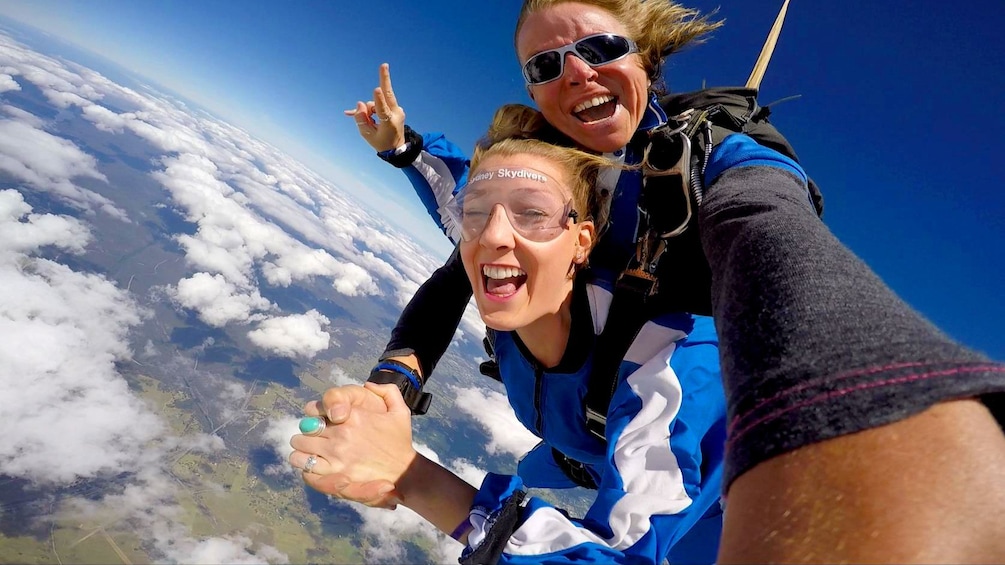 Show item 4 of 4. Two skydivers fastened together falling over Sydney.