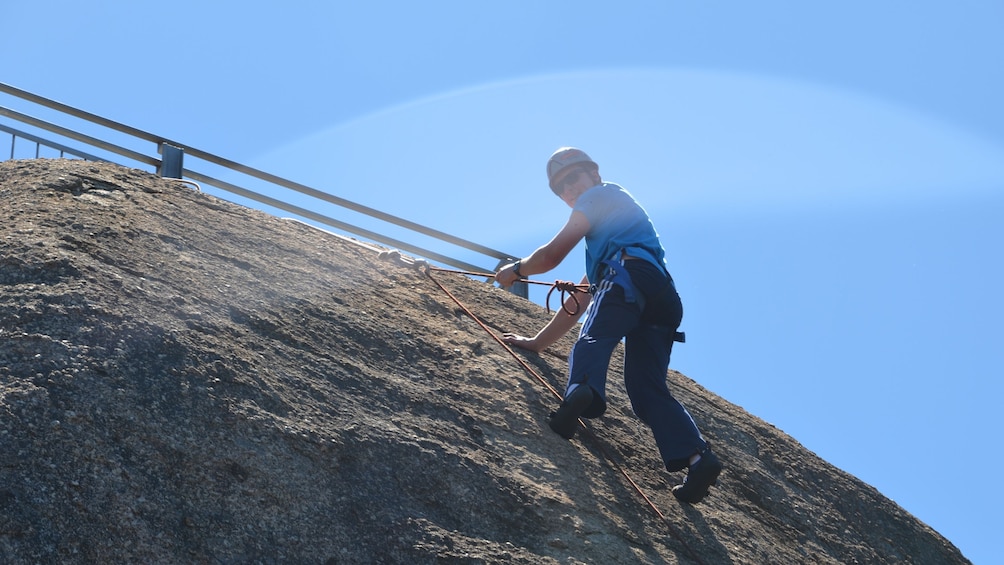 man in safety gear begins his descent of rocky wall in Melbourne