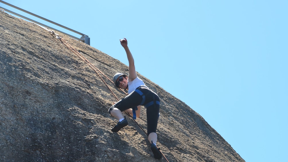 woman in safety harness climbs rock wall in Melbourne