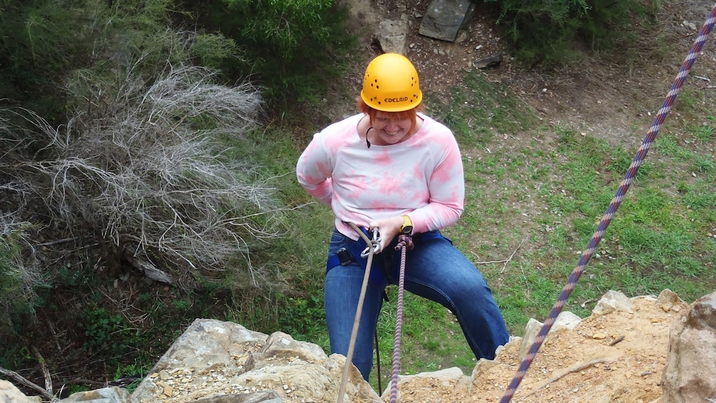 woman in safety harness repels down rock wall in Melbourne