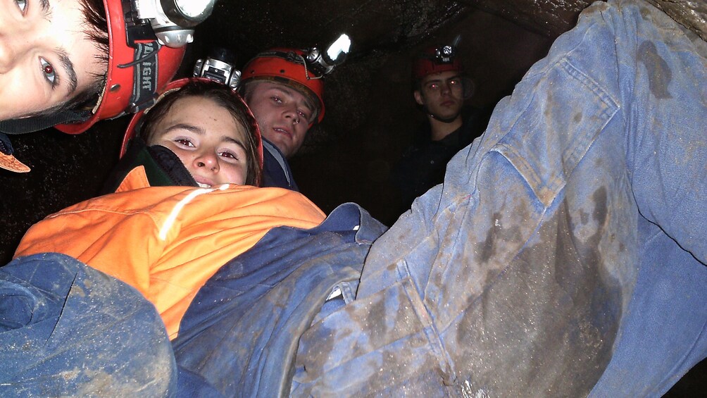 group of mens in safety gear explore dark cave.