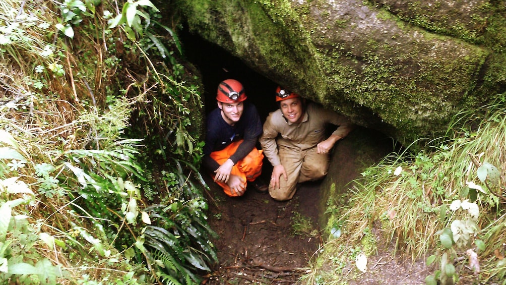 two men crouched by cave opening in Melbourne 