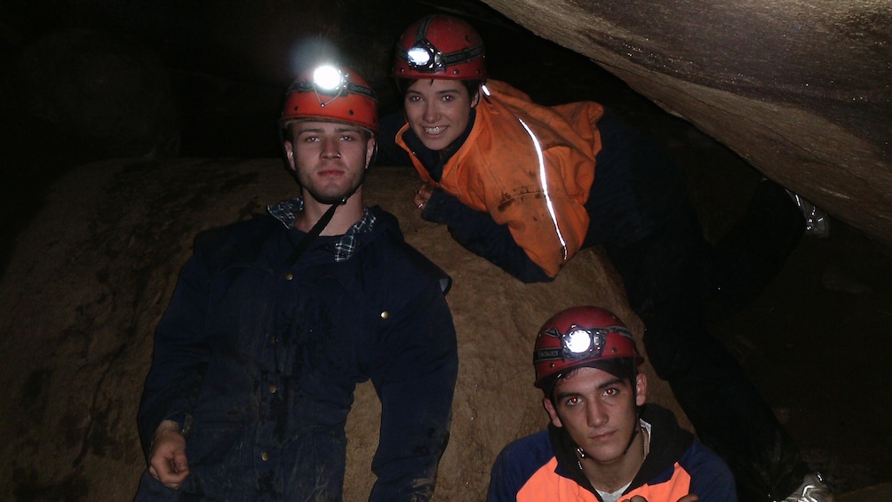 three men in safety gear inside dark cave in Melbourne