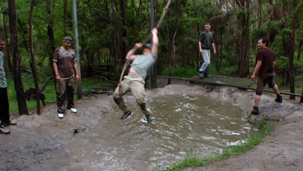 man swings over water in obstacle course in Melbourne