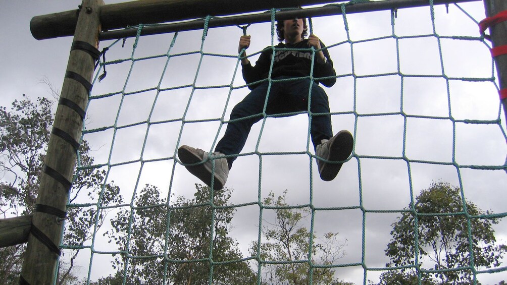 man climbs netting in obstacle course in Melbourne