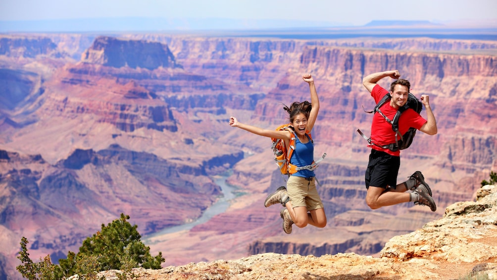 Couple jump for joy while basking in the majestic views of the Grand Canyon