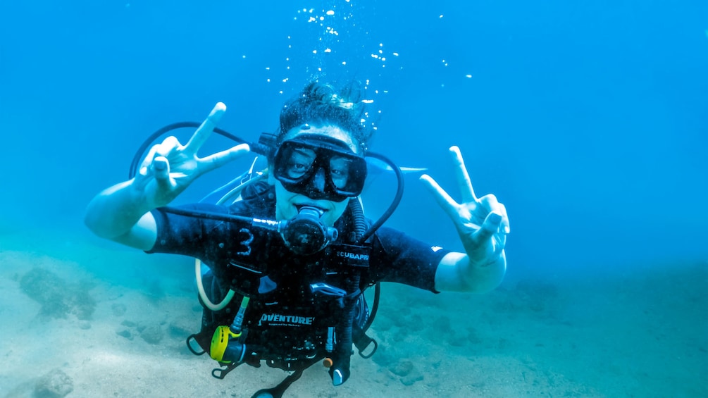 Scuba diving woman flashing peace signs in Puerto Vallarta.