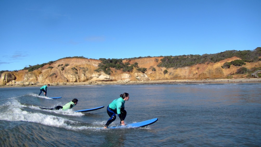 Show item 4 of 5. People surfing on a small wave to the shore of the Great Ocean Road in Australia