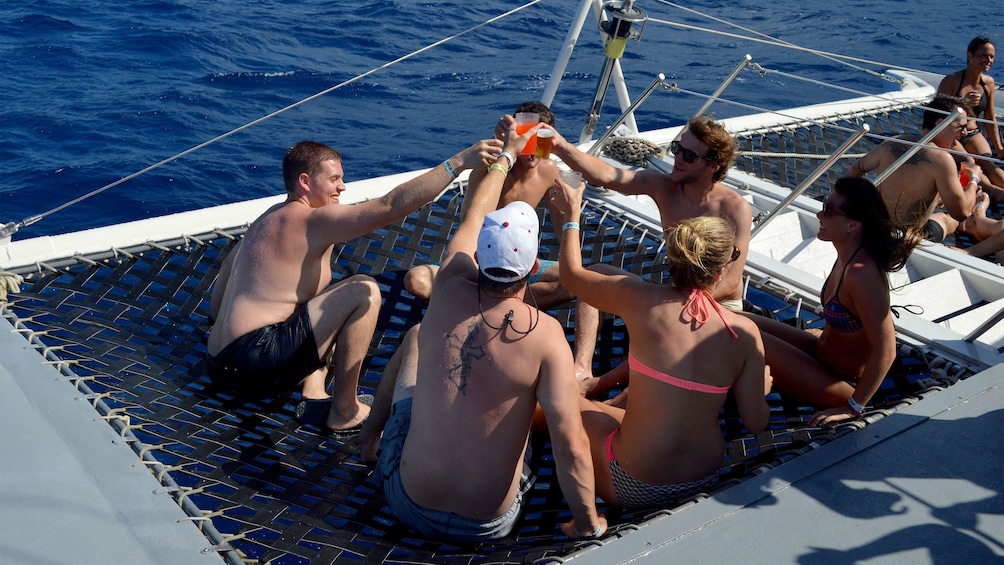 Group of people enjoy drinks and the sun on a sail boat near Nevis