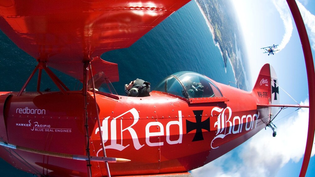 red bi-plane being chased by another bi-plane in Sydney