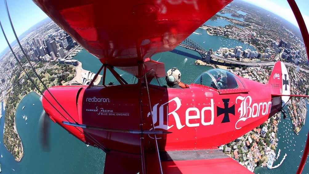 red bi-plane flying upside down in Sydney