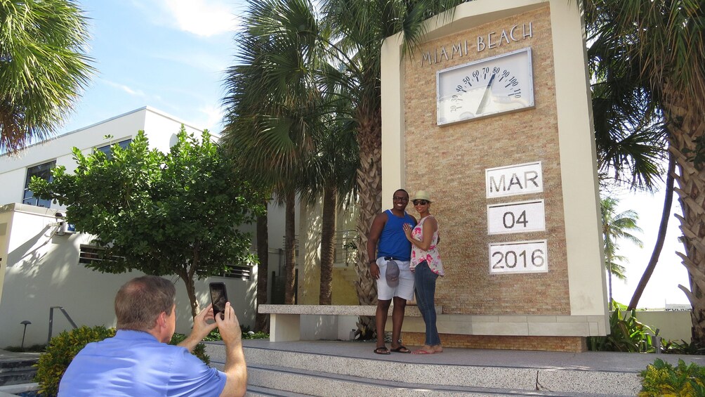 Couple stands next to large thermometer